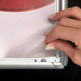 Hand wechselt Poster in Aluminium-Klapprahmen